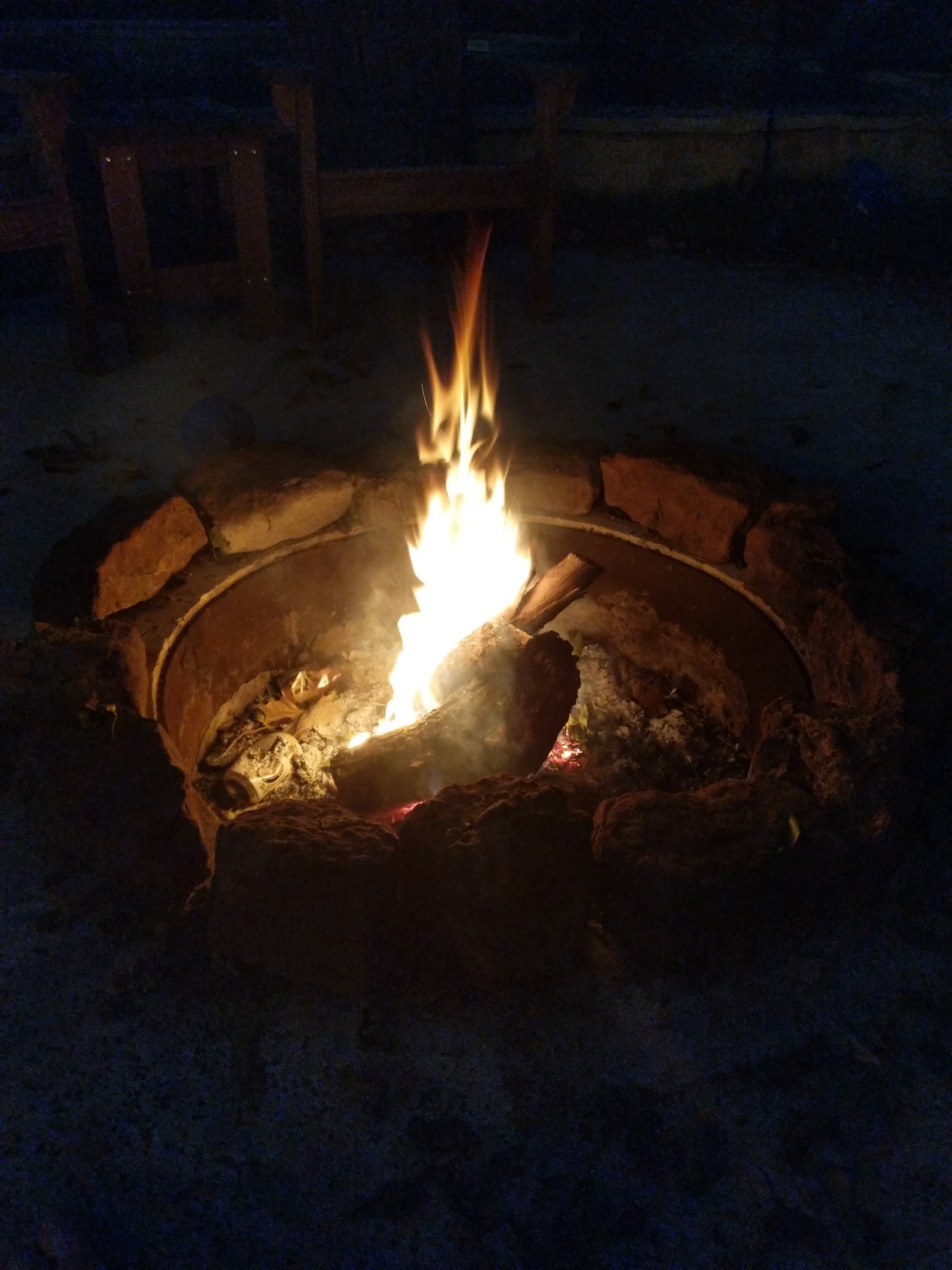 A fire burning in the stone fire pit at night